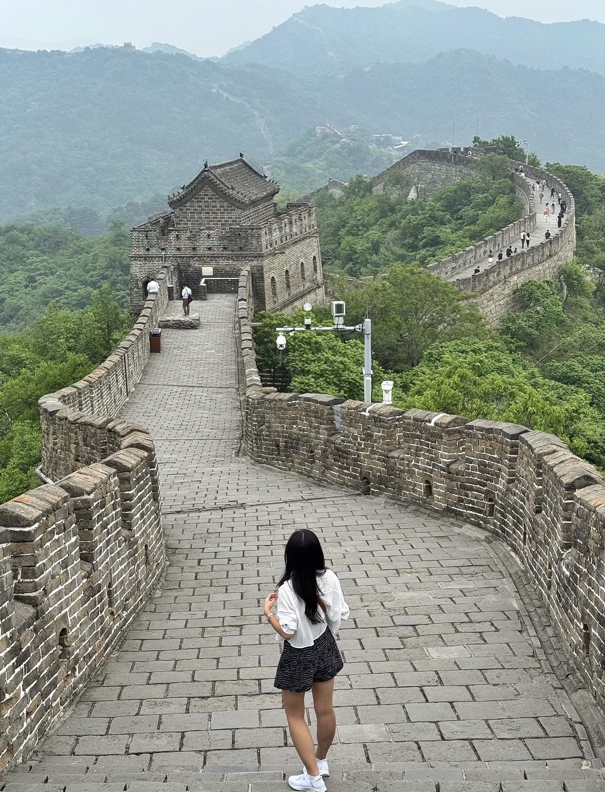 Local guide explaining Ming-dynasty watchtower architecture to a group of tourists on the Great Wall of China