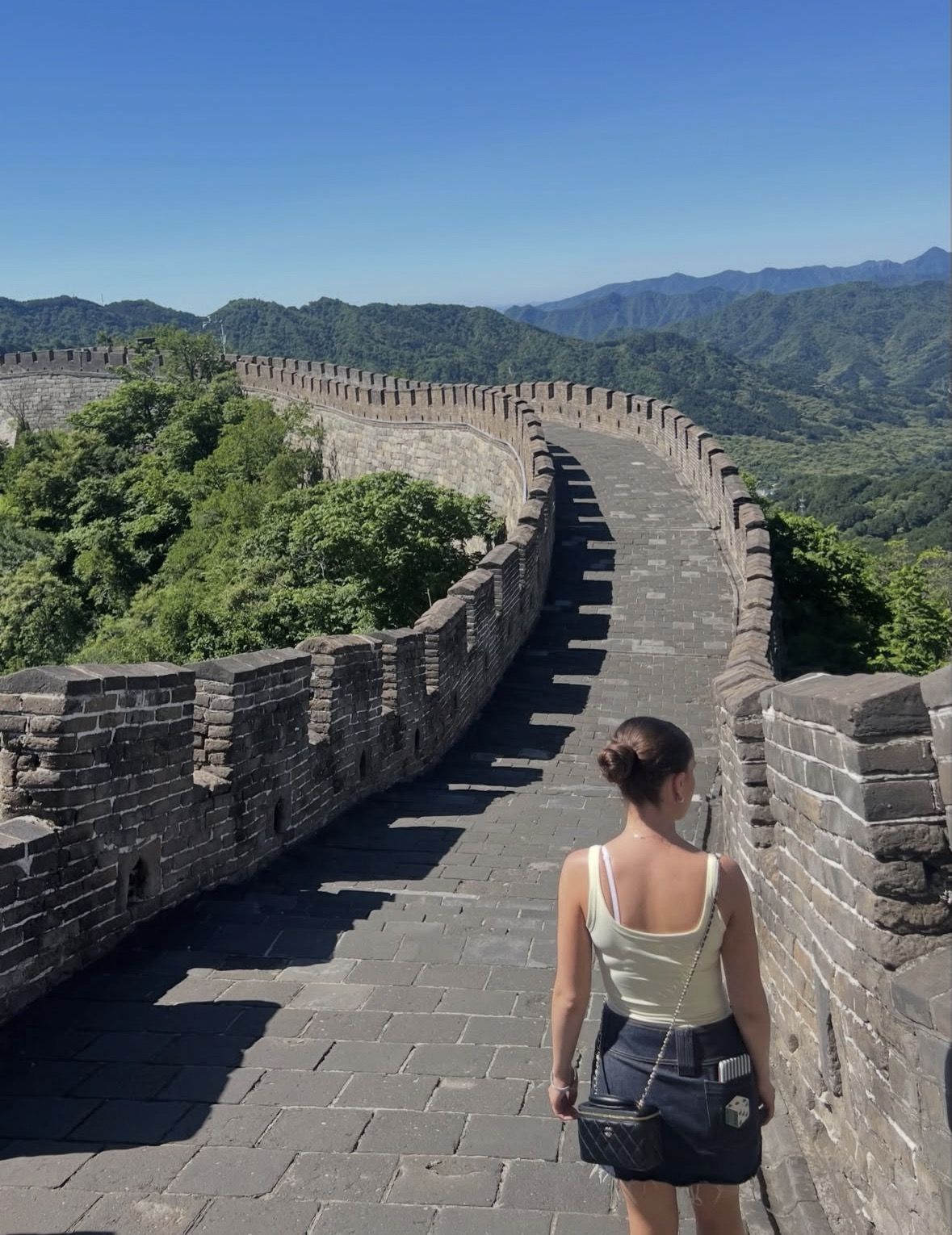 Hiker with a daypack and trekking poles ascending stone steps along the Great Wall of China